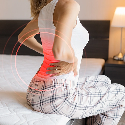 Woman Sitting On A Bed With Highlighted Back Pain
